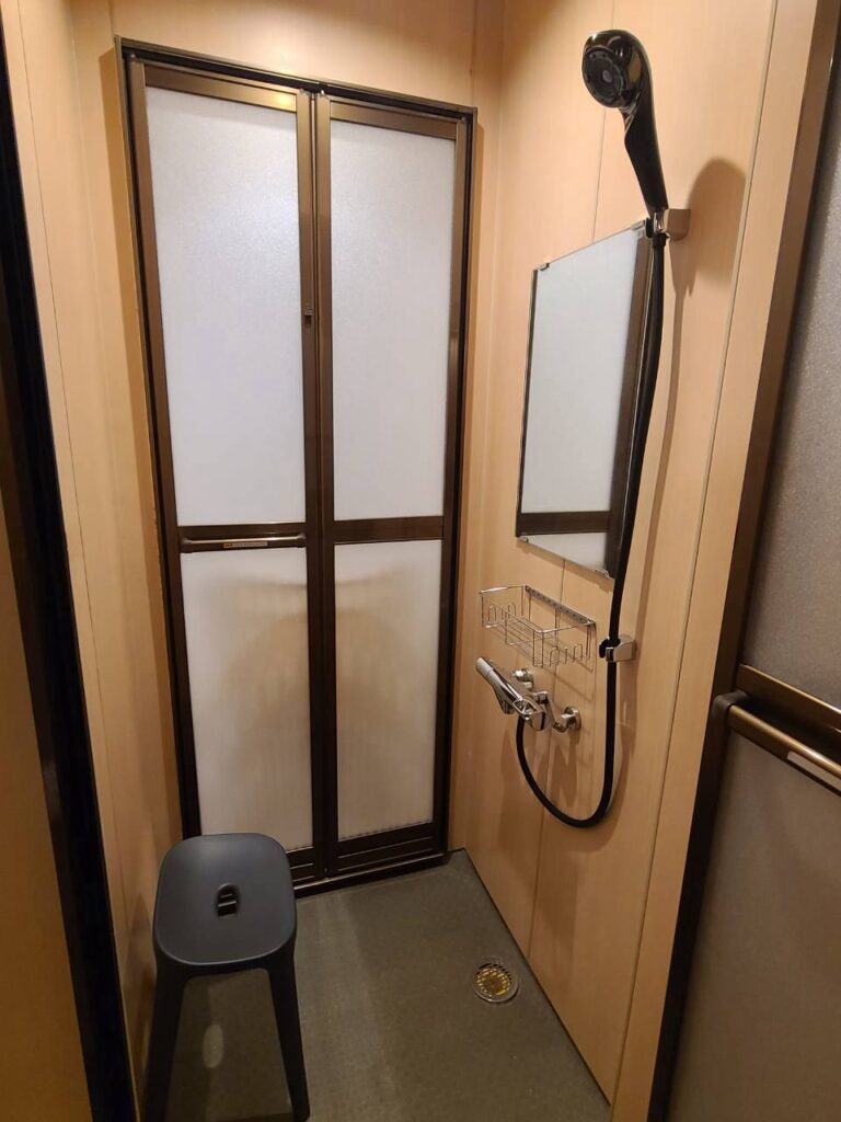個室のシャワールーム。シャワーヘッドとアメニティを備えた洗い場