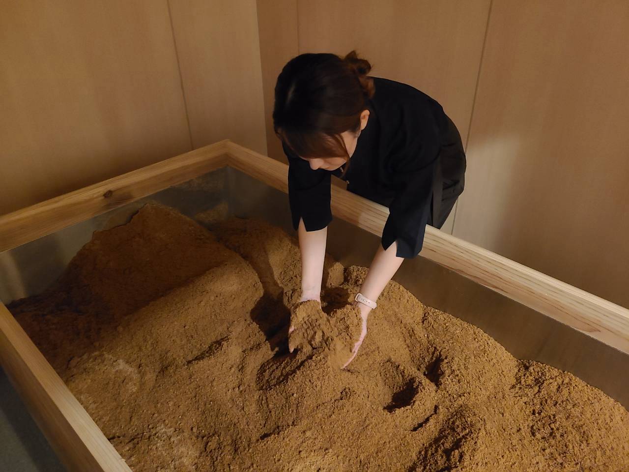 木の桶の浴床に両手を添えてお手入れをする店長