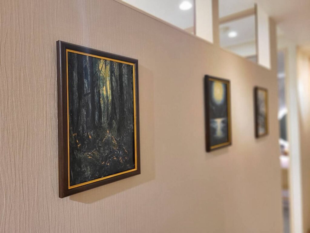 通路の壁に飾ったアートHRの油絵。手前に森の木漏れ日を描いた「深」、奥に続く額装作品