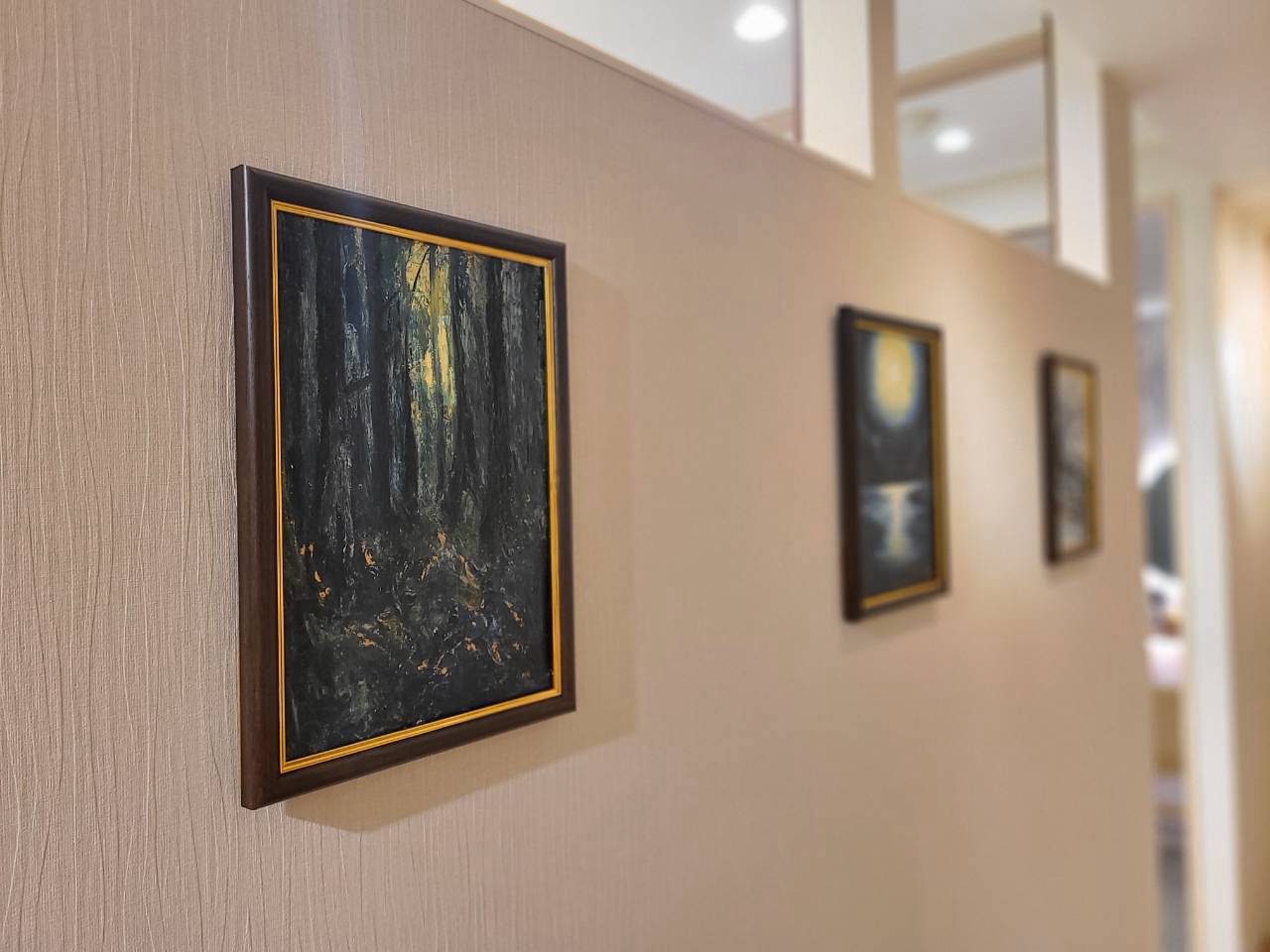通路の壁に飾ったアートHRの油絵。手前に森の木漏れ日を描いた「深」、奥に続く額装作品