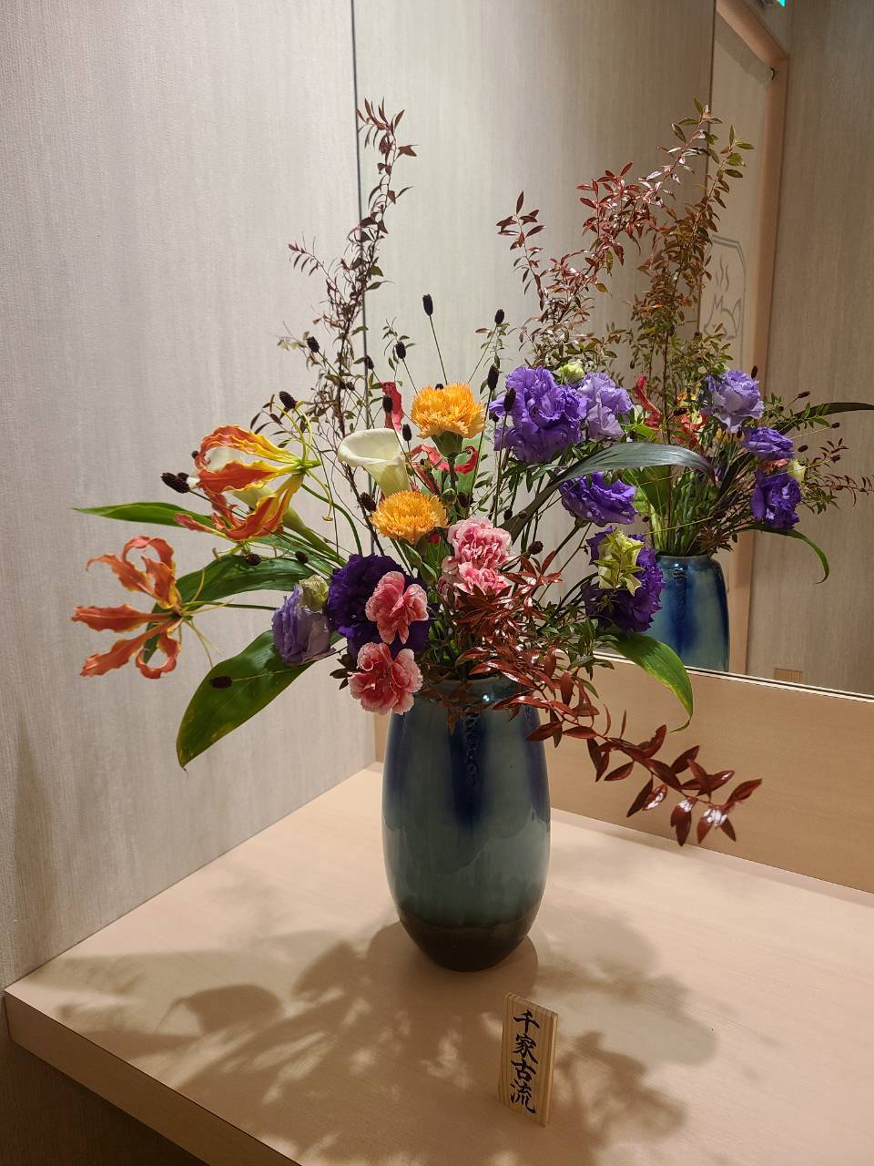 10月7日に新しく生けた紫・橙・桃色の花と枝物。青緑の花器に飾った、紺-Kon-の店内の生け花